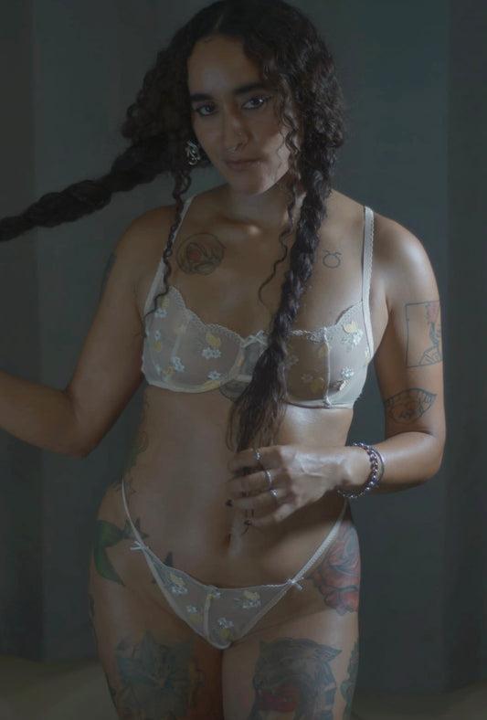 Woman wearing an embroidered floral lingerie set against a neutral background